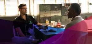 deux hommes assis à un bureau se parlent