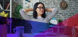 a woman with her hands behind her head, relaxing at her desk